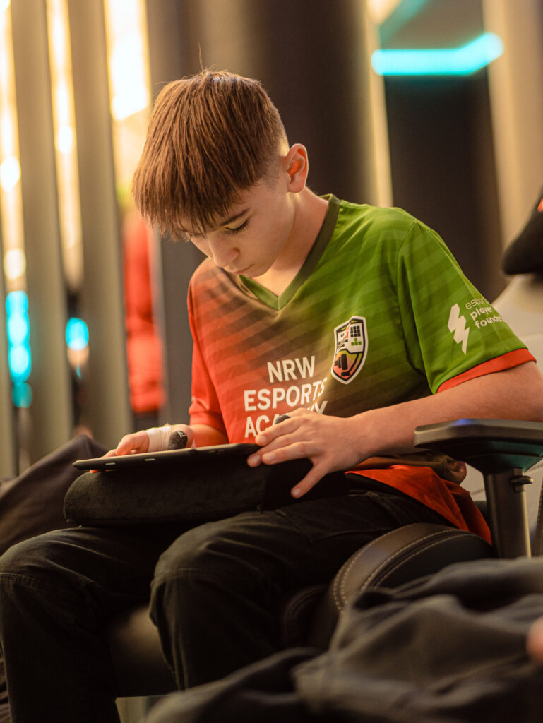 Esports Academy NRW - Ben W. spielt am Ipad Brawlstars. Er schaut nach unten und trägt ein Trikot in Rot & grün. Bereits in Jungen Jahren ist er Teil der Talentförderung geworden.