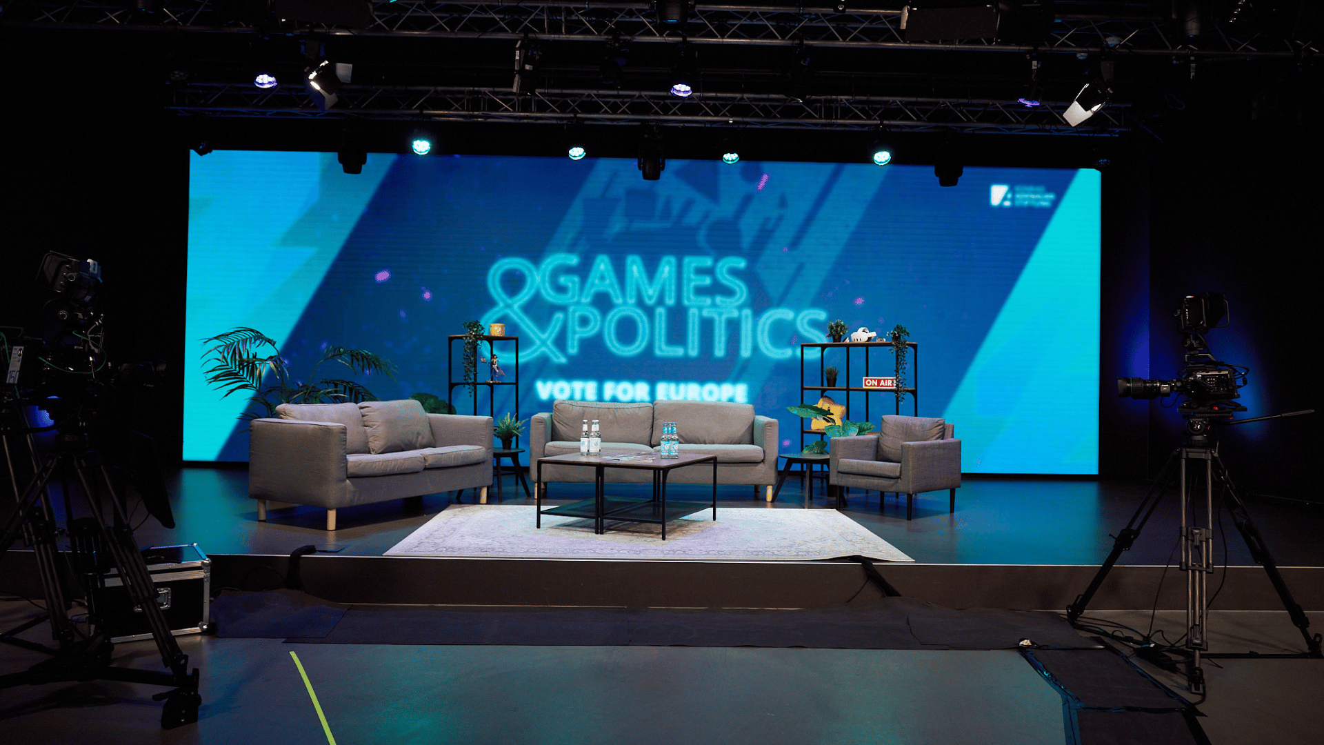 Bühne der Show Games&Politics, welche live auf Twitch ausgestrahlt wurde, mit der Unterüberschrift Vote for Europe. Es stehen 5 Sessel auf der Bühne und im Hintergrund ist das Games&Politics Vote for Europe Logo samt Schriftzug auf einem LED Screen zu sehen.